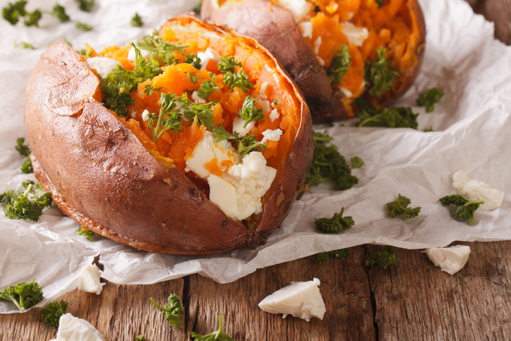healthy food: baked sweet potato stuffed with cheese and parsley close-up. Vertical